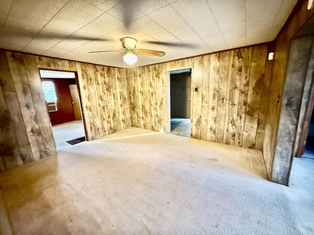 spare room with ceiling fan, wooden walls, cooling unit, and carpet flooring