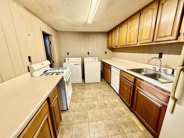 kitchen featuring white appliances, brown cabinets, washing machine and clothes dryer, light countertops, and a sink