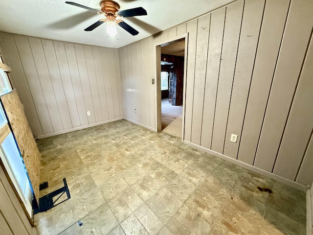 empty room featuring a textured ceiling, a ceiling fan, and baseboards