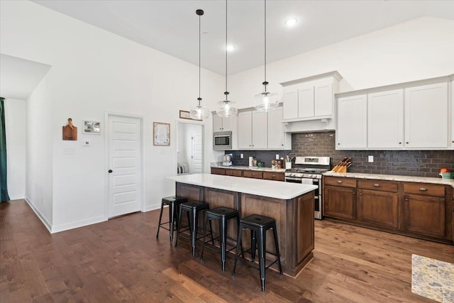 kitchen featuring a breakfast bar, dark wood-style flooring, light countertops, appliances with stainless steel finishes, and a kitchen island