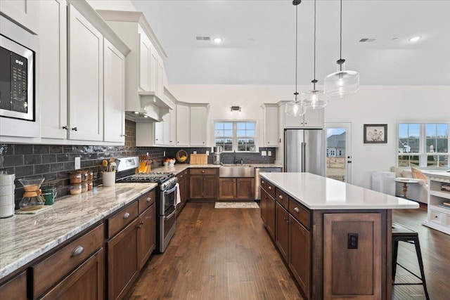 kitchen with a breakfast bar, a kitchen island, a sink, appliances with stainless steel finishes, and decorative backsplash