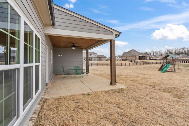 exterior space with a playground, fence, and ceiling fan