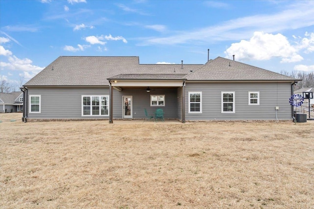 rear view of property featuring a shingled roof, central air condition unit, ceiling fan, and a lawn