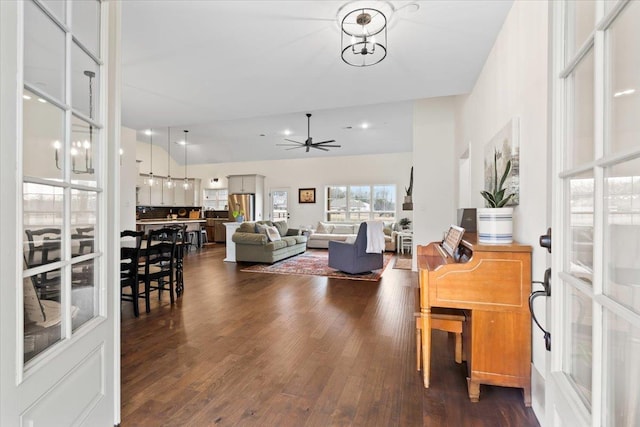 interior space featuring ceiling fan with notable chandelier, dark wood-type flooring, and lofted ceiling