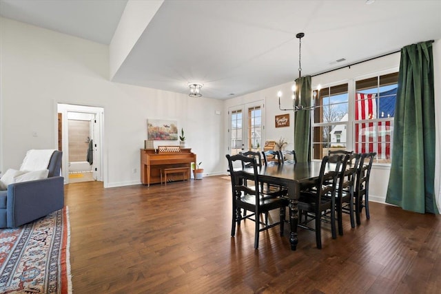 dining space featuring baseboards, a chandelier, and wood finished floors