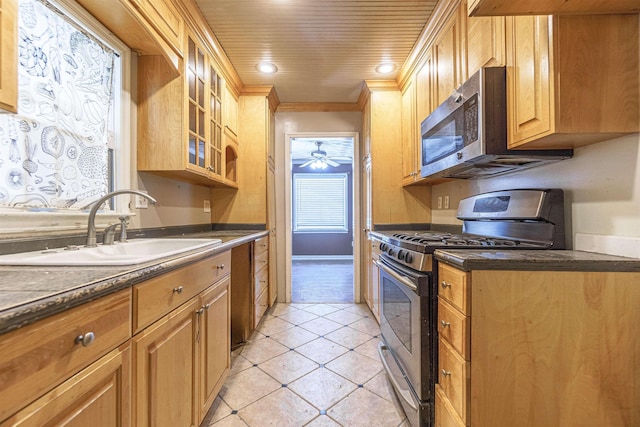 kitchen featuring light tile patterned flooring, stainless steel appliances, a sink, dark countertops, and crown molding