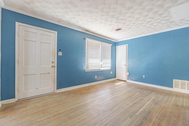 unfurnished room featuring ornamental molding, visible vents, baseboards, and wood finished floors