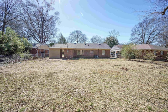 back of property with a fenced backyard, a lawn, and brick siding