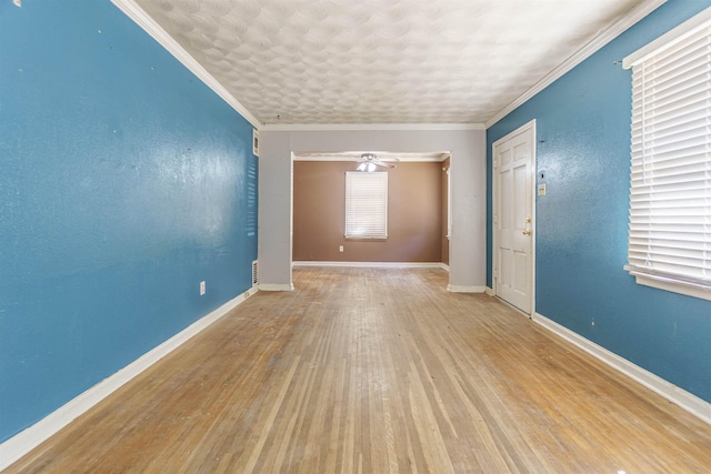 unfurnished room with ornamental molding, a textured wall, baseboards, and wood finished floors