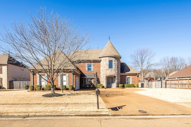 french country style house with brick siding, concrete driveway, fence, a garage, and stone siding