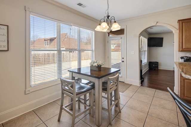 dining space with arched walkways, visible vents, crown molding, and light tile patterned floors