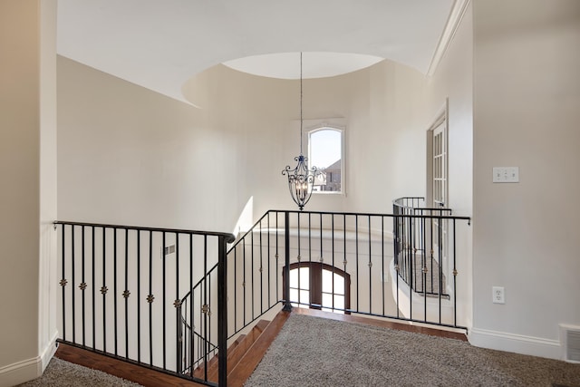 corridor featuring an upstairs landing, visible vents, baseboards, and an inviting chandelier