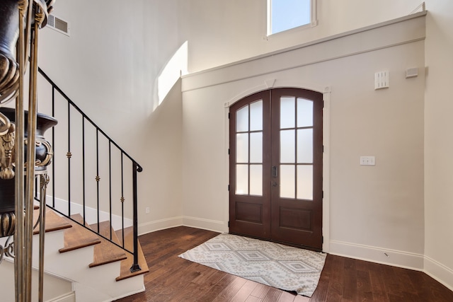 foyer with arched walkways, hardwood / wood-style flooring, stairway, a high ceiling, and french doors