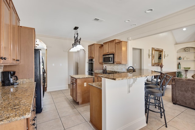 kitchen with visible vents, backsplash, appliances with stainless steel finishes, light tile patterned flooring, and a kitchen island