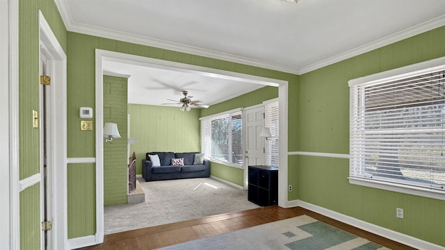 interior space with a ceiling fan, crown molding, baseboards, and wood finished floors