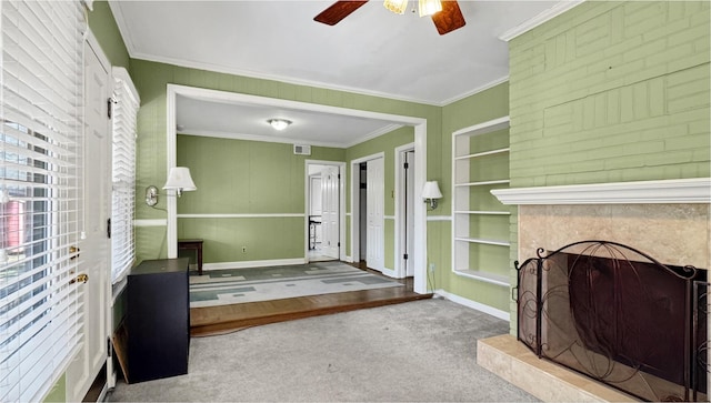 unfurnished living room featuring carpet floors, a large fireplace, baseboards, and crown molding