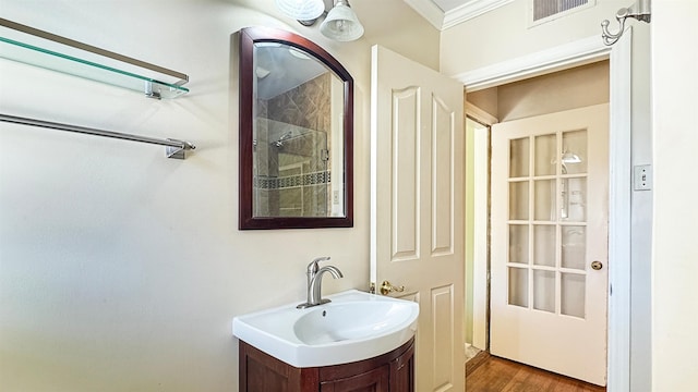 bathroom featuring wood finished floors, vanity, visible vents, walk in shower, and crown molding