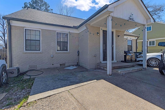 rear view of property featuring crawl space, a shingled roof, fence, and brick siding