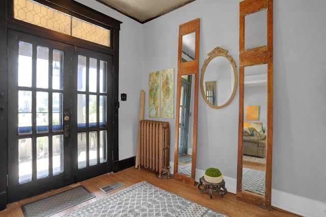 foyer with wood finished floors, visible vents, baseboards, french doors, and radiator