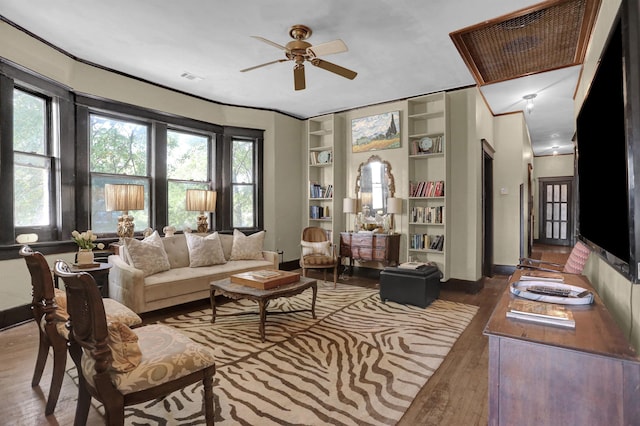 living room featuring hardwood / wood-style flooring, built in shelves, visible vents, and a wealth of natural light