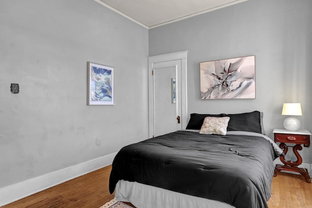 bedroom featuring crown molding, wood finished floors, and baseboards