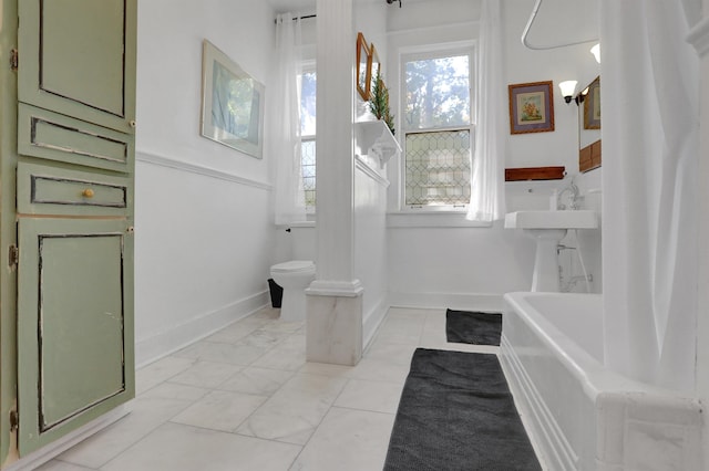 full bath with marble finish floor, a washtub, toilet, and baseboards