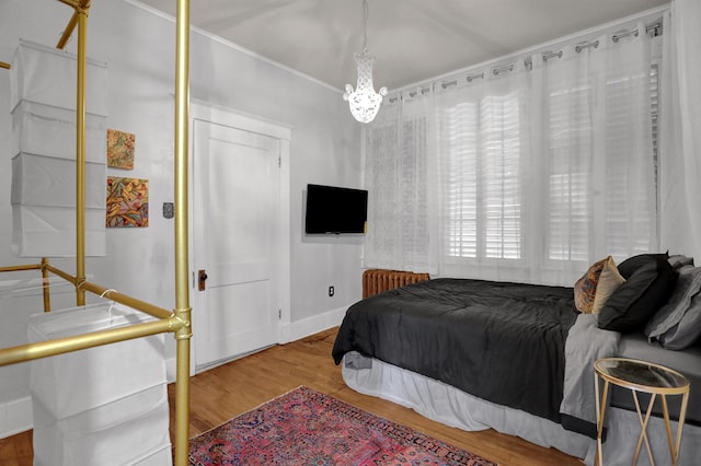 bedroom with baseboards, a chandelier, and wood finished floors