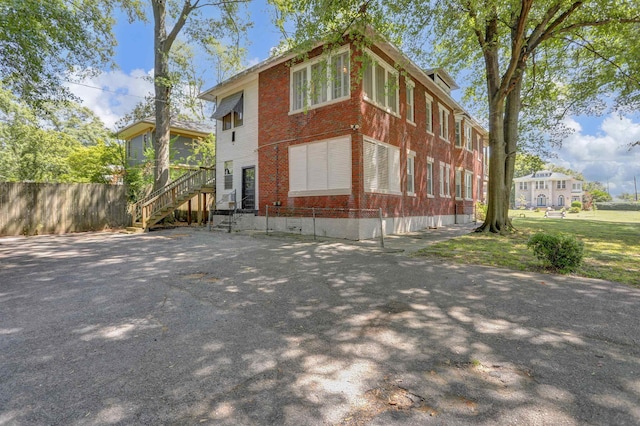 view of property exterior featuring fence and brick siding