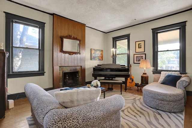 living area with light wood finished floors, visible vents, ornamental molding, a textured ceiling, and a fireplace