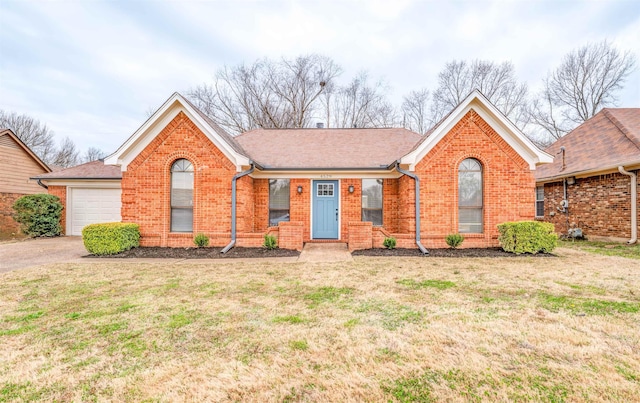 ranch-style home with a garage, a shingled roof, a front lawn, and brick siding