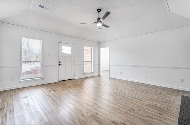 foyer with a textured ceiling, wood finished floors, visible vents, a ceiling fan, and vaulted ceiling