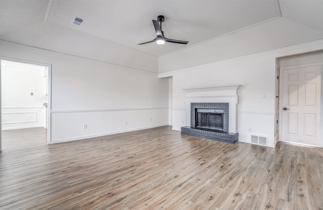 unfurnished living room featuring ceiling fan, a fireplace, visible vents, and wood finished floors