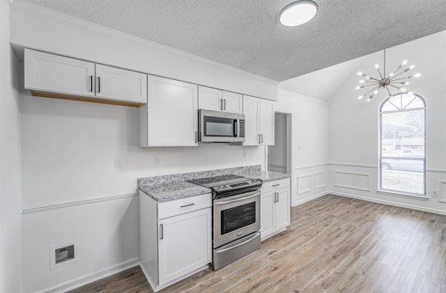 kitchen with white cabinets, light stone countertops, light wood-type flooring, and stainless steel appliances