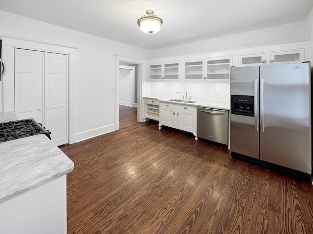 kitchen with stainless steel appliances, a sink, white cabinetry, light countertops, and dark wood-style floors