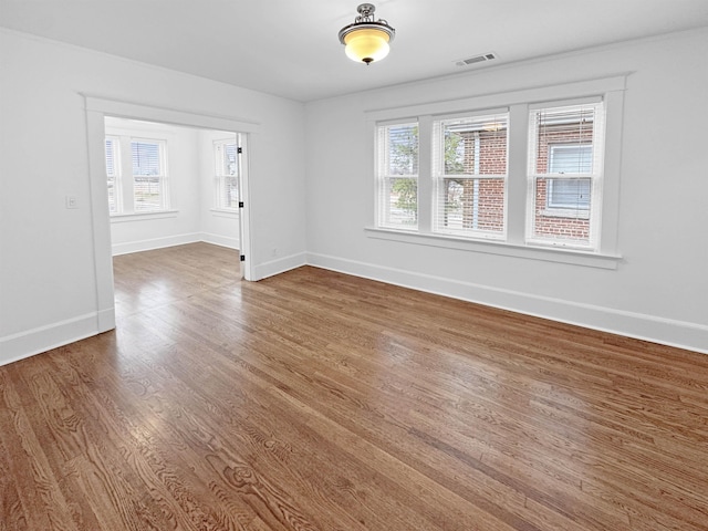 unfurnished room with wood finished floors, visible vents, and baseboards