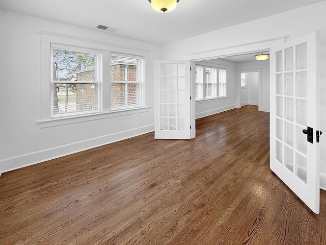 unfurnished room featuring dark wood-style flooring, visible vents, baseboards, and french doors