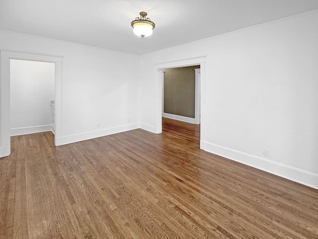 spare room with baseboards and wood finished floors