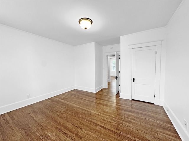 unfurnished room featuring dark wood-style floors, crown molding, and baseboards