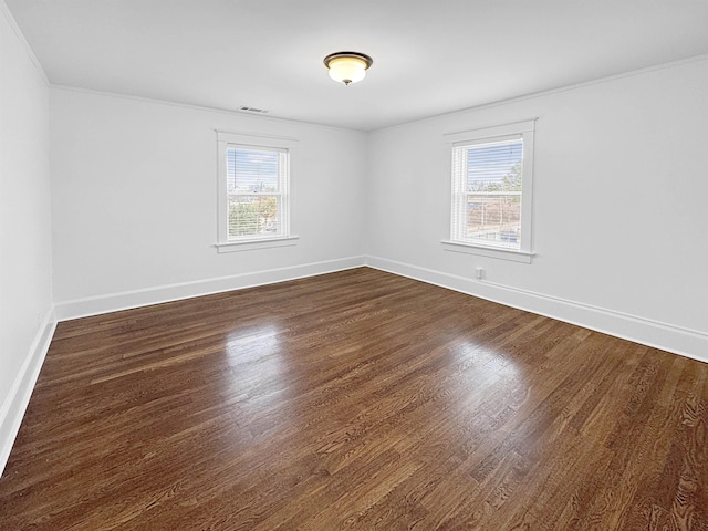 spare room featuring baseboards, plenty of natural light, visible vents, and dark wood-style flooring