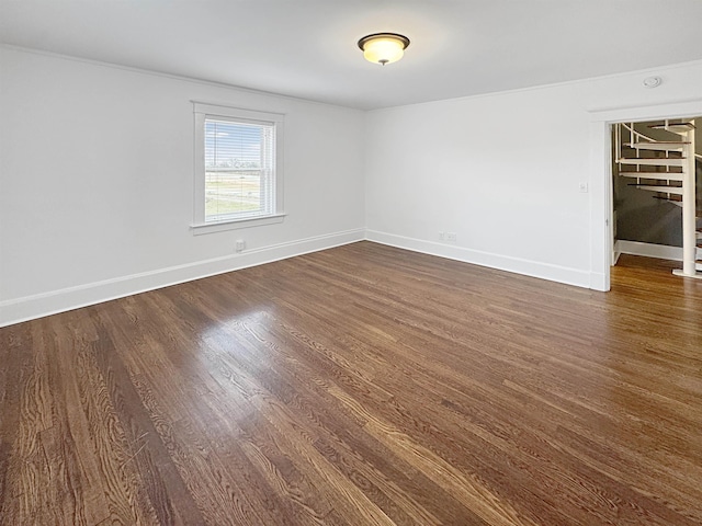 unfurnished room with dark wood-style flooring and baseboards