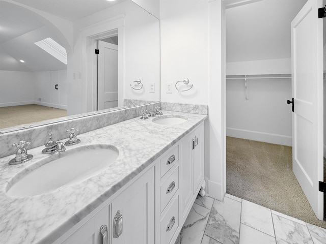 bathroom featuring double vanity, marble finish floor, vaulted ceiling, and a sink