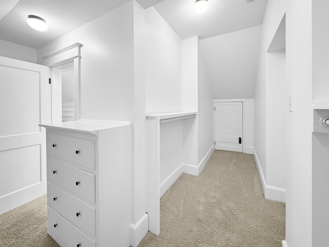 hallway featuring carpet, vaulted ceiling, and baseboards