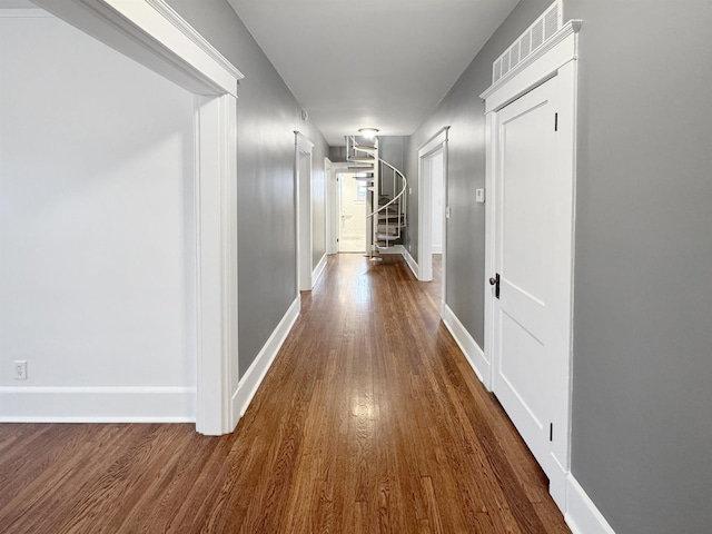 hall with dark wood-type flooring, visible vents, baseboards, and stairs