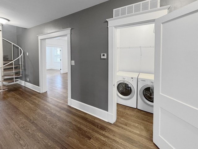 laundry room featuring laundry area, wood finished floors, washing machine and dryer, and baseboards