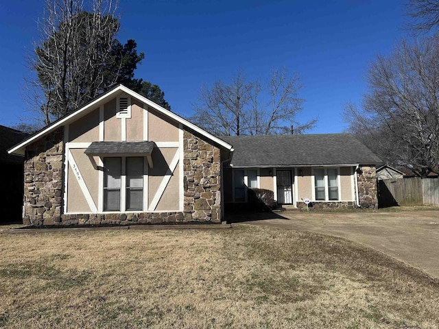 view of front of house featuring stone siding, a front yard, fence, and stucco siding