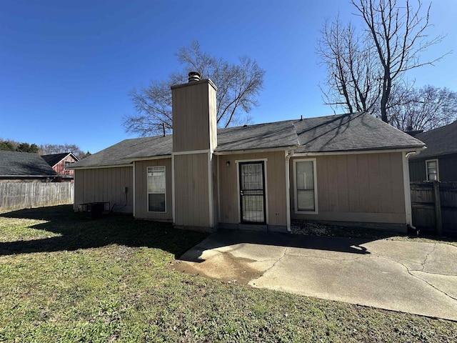 back of property with a patio area, a chimney, fence, and a yard