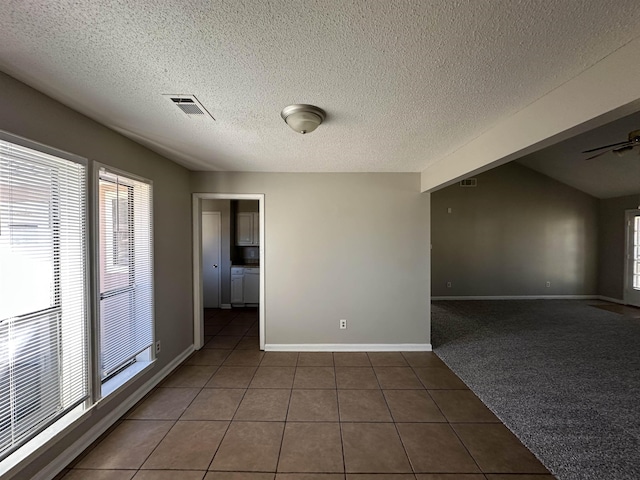 tiled spare room featuring baseboards, visible vents, ceiling fan, and a textured ceiling