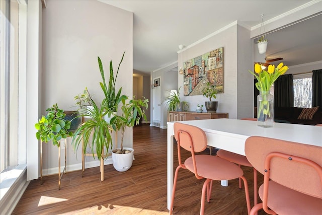 dining area featuring baseboards, crown molding, and wood finished floors