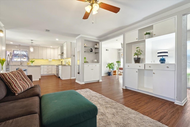 living room with dark wood-style floors, visible vents, ornamental molding, and baseboards