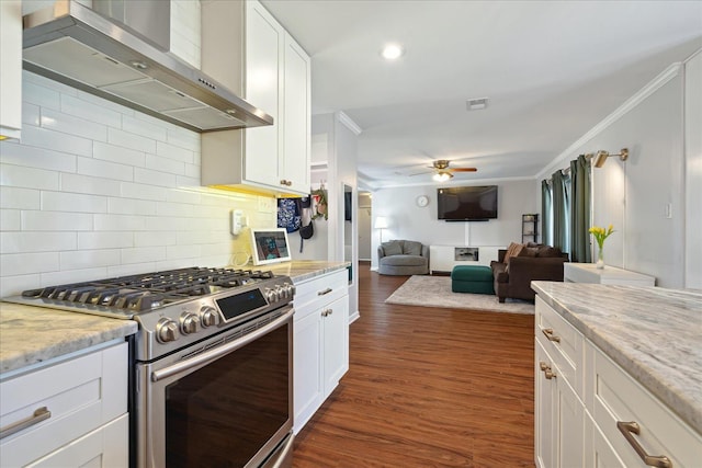 kitchen with stainless steel gas stove, wall chimney exhaust hood, ceiling fan, ornamental molding, and dark wood-type flooring